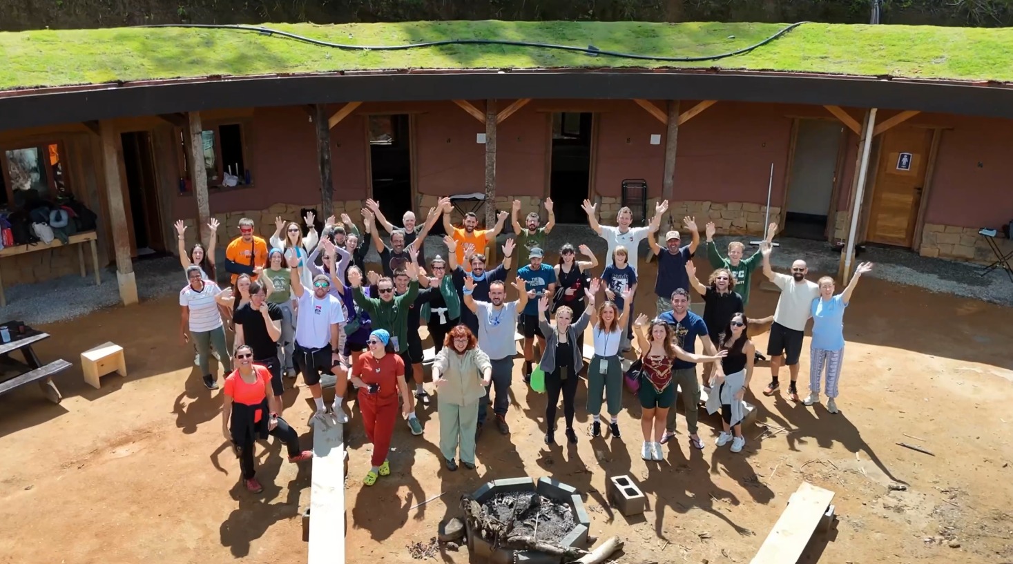 Resumen de Noviembre y Diciembre 2025 6 Gran grupo de voluntarios griegos celebrando frente a una bioconstrucción con techo verde en la finca Eco Caminhos.