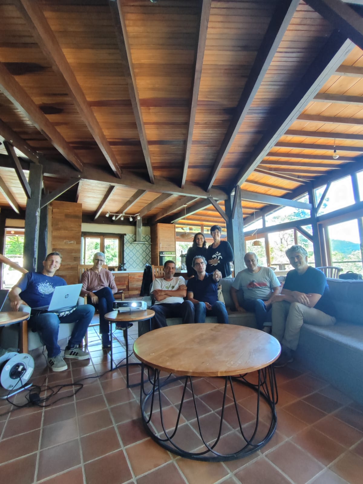 Resumen de Noviembre y Diciembre 2025 8 Miembros de la junta de la Asociación Ecolibrium en reunión estratégica dentro de un ecolodge de madera con vista a la naturaleza.