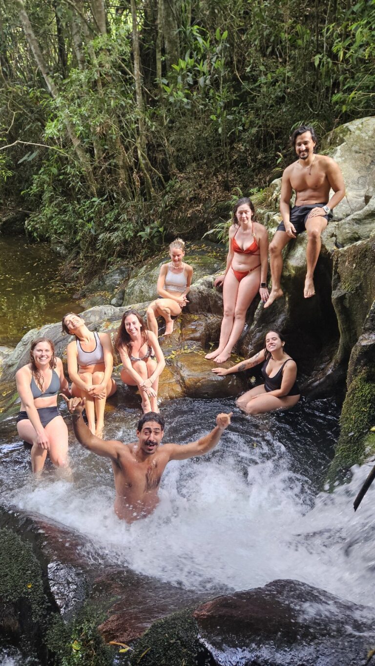 International volunteers relaxing at a beautiful waterfall after participating in eco farm activities in Brazil.