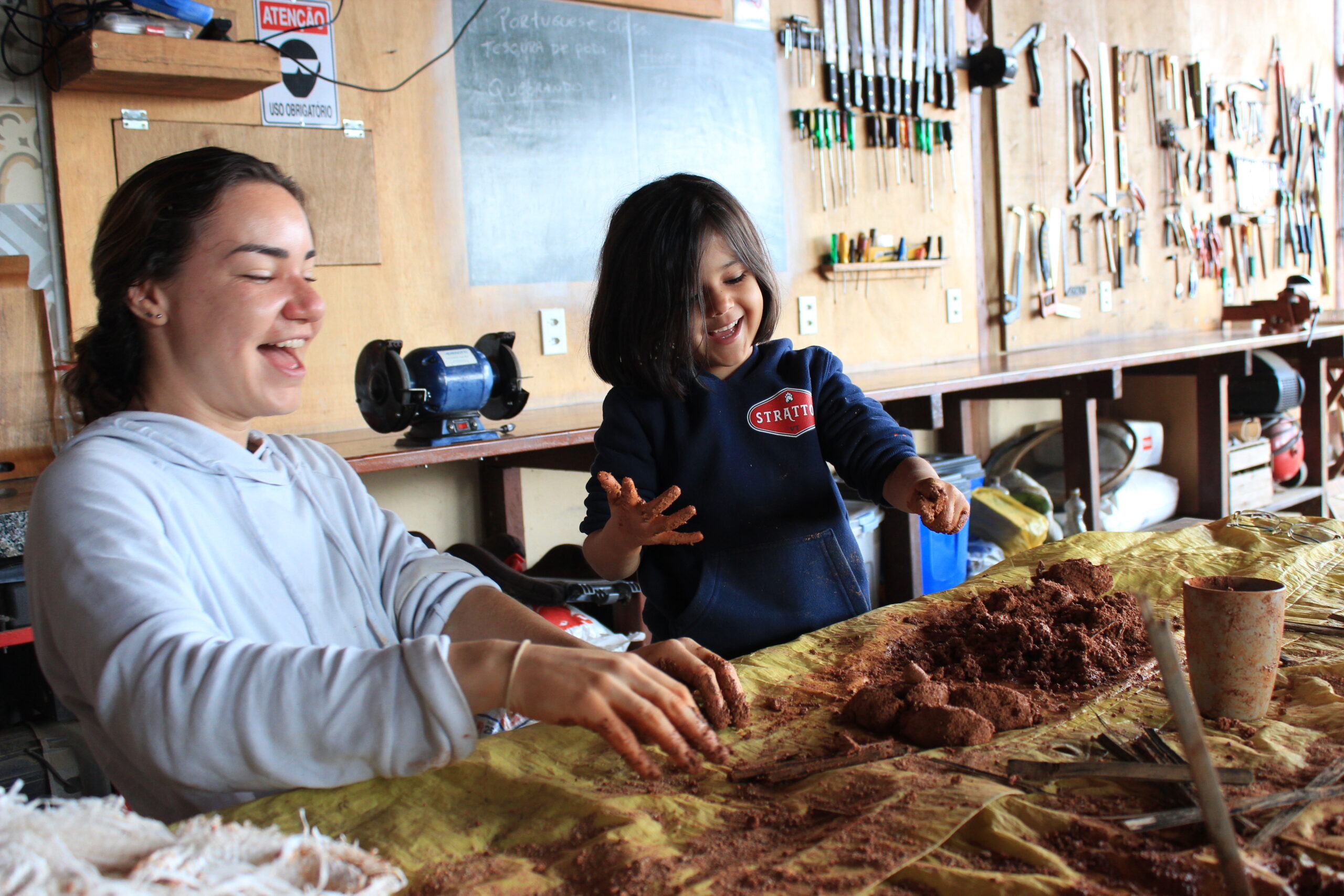 Volunteer and child creating handmade pottery during a sustainable living experience at a permaculture farm in Brazil.
