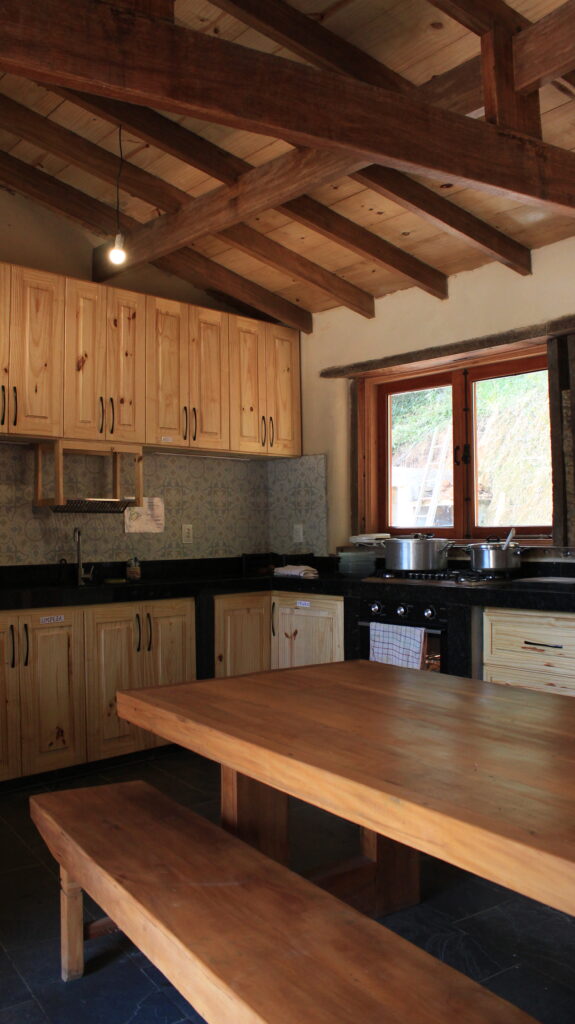 Natural building kitchen with large wooden table inside an eco farm Brazil home