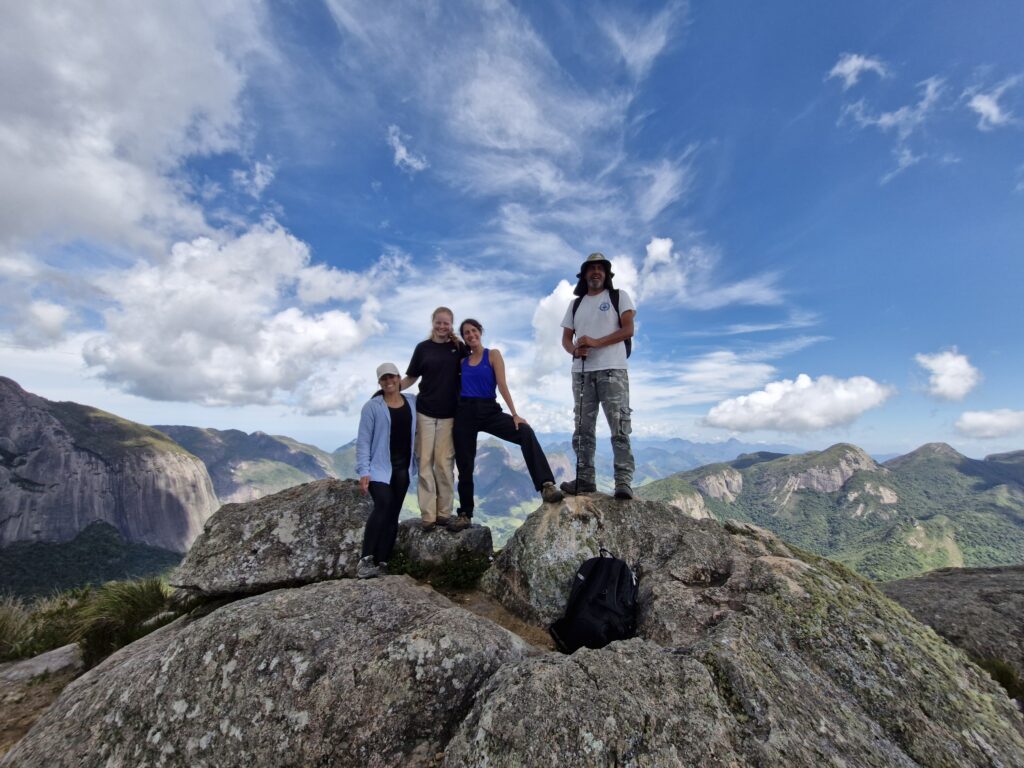 Volunteers celebrating at the summit of Dragon's Head Mountain during an ecotourism adventure in Brazil.
