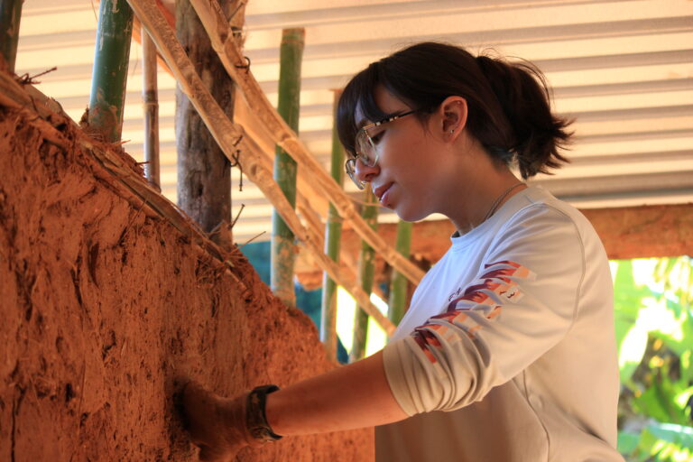 Participant working with natural materials during a sustainable building workshop.