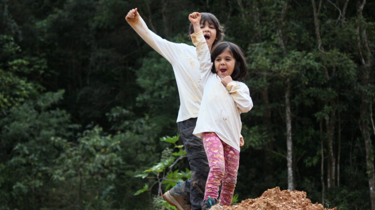 Two children enjoying outdoor activities on an eco farm in Brazil surrounded by nature.