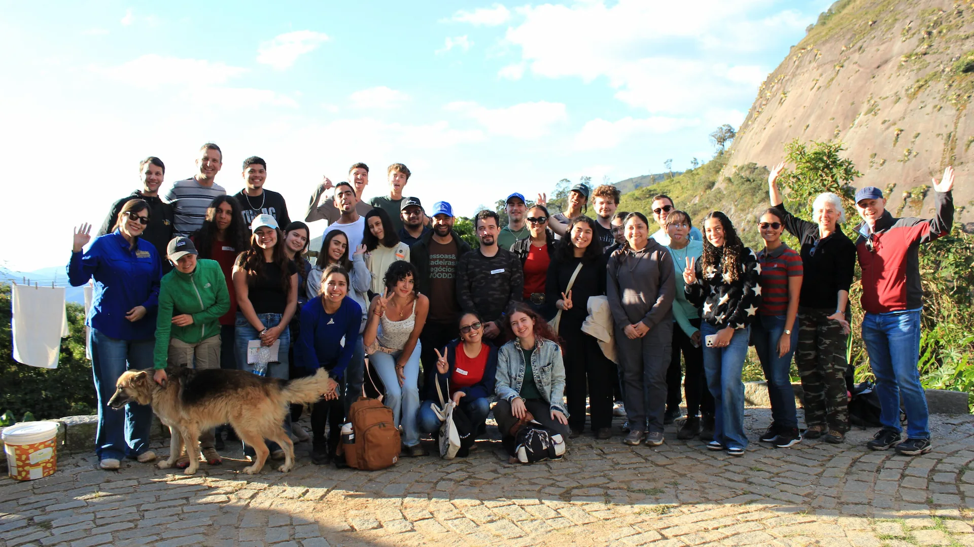 Group posing outdoors with a mountain landscape and dog at Eco Caminhos.
